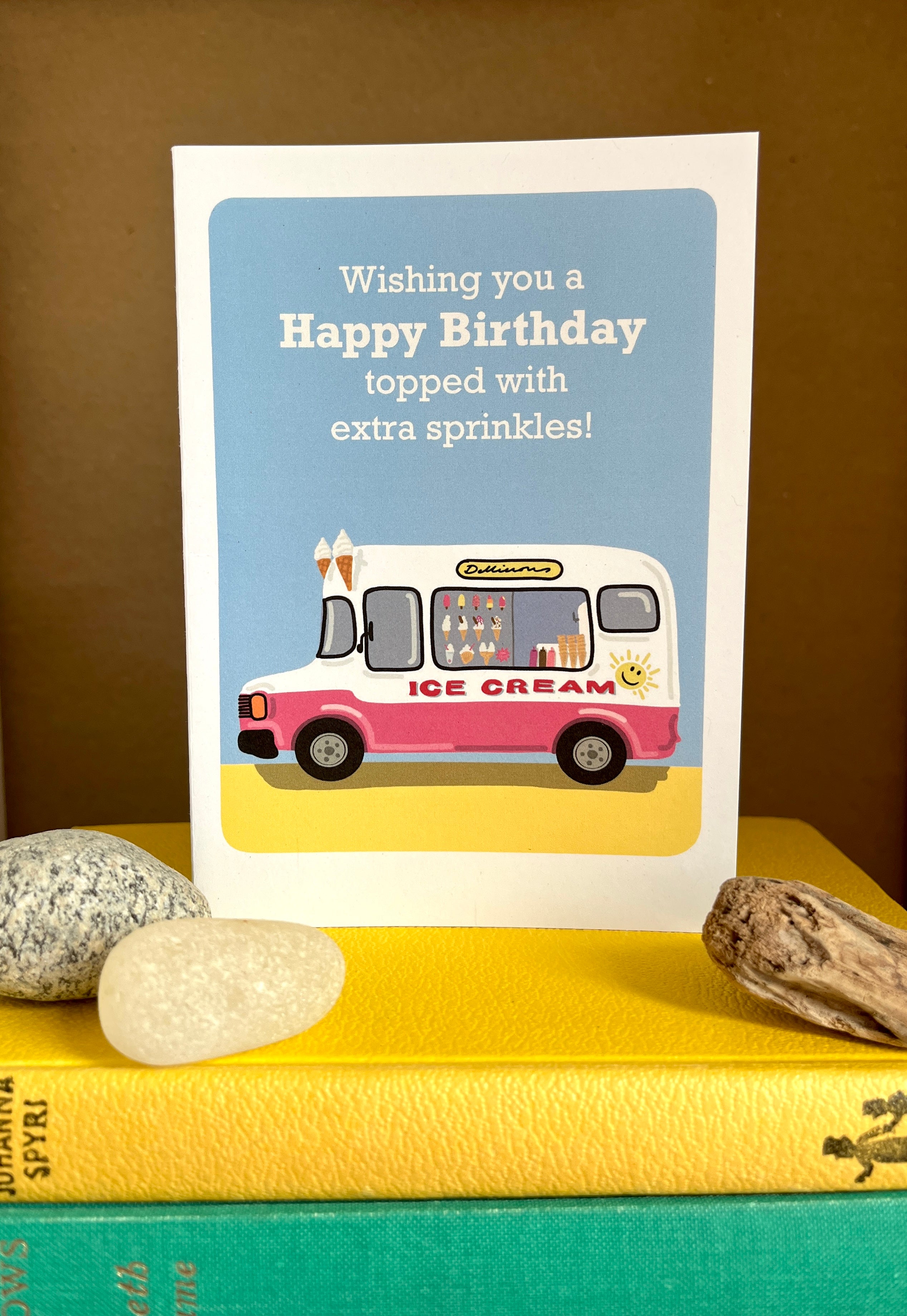Birthday card with ice cream truck illustration and text on a yellow surface.