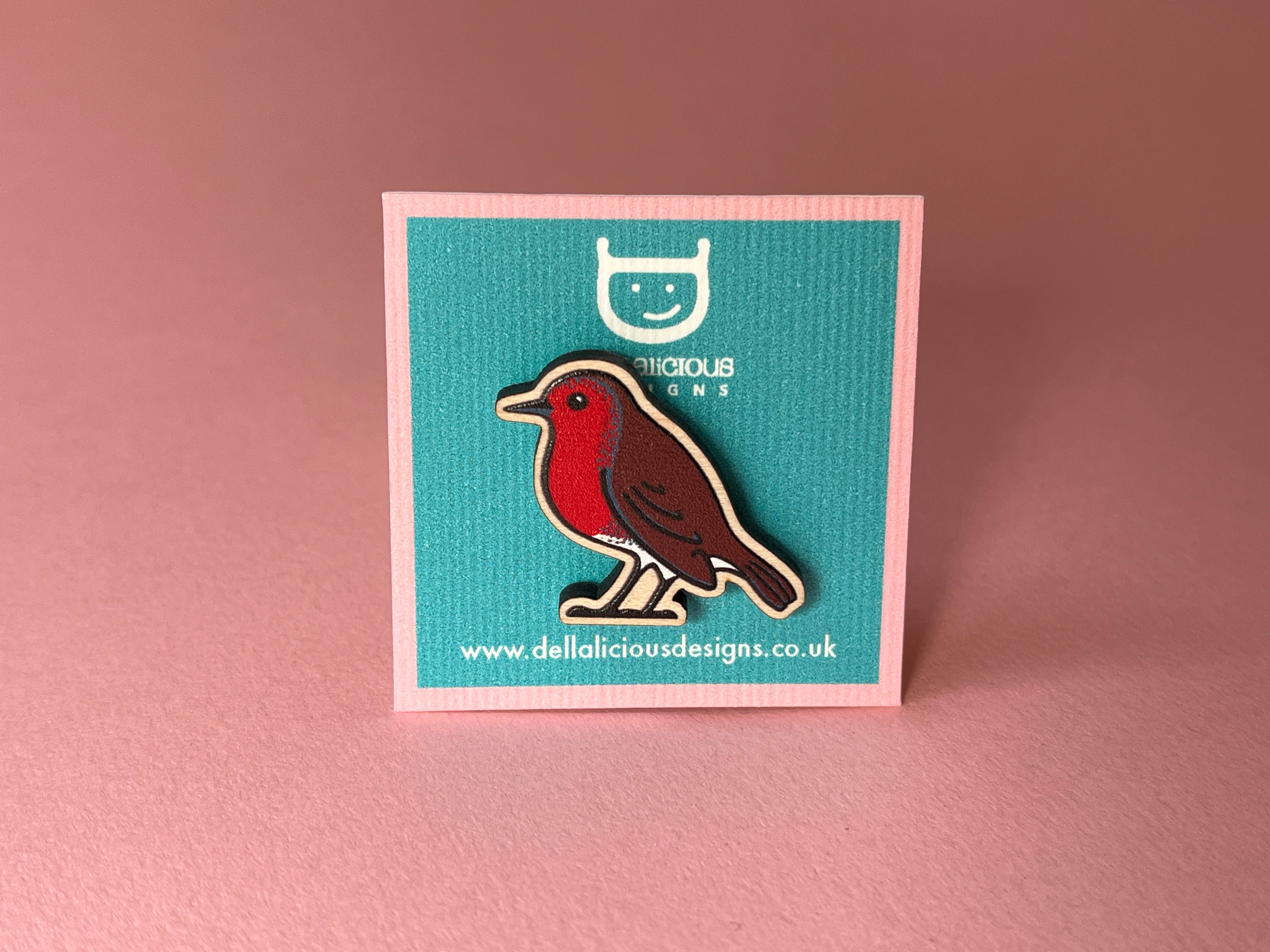 Robin badge on a teal card with a logo and website text, against a pink background