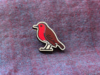 Bird-shaped pin on a textured fabric background