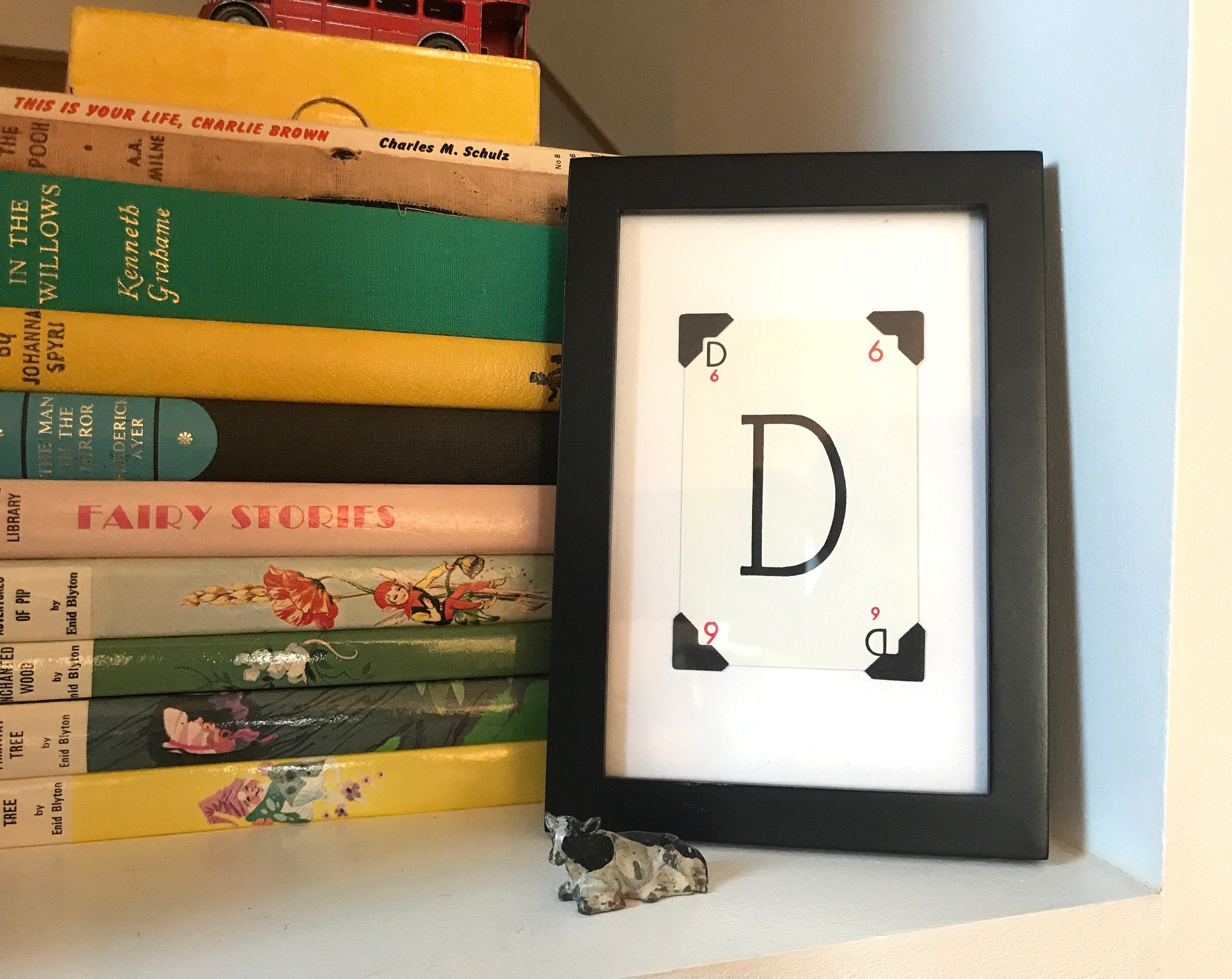 A black framed picture with a white background and a large capital letter D in black.