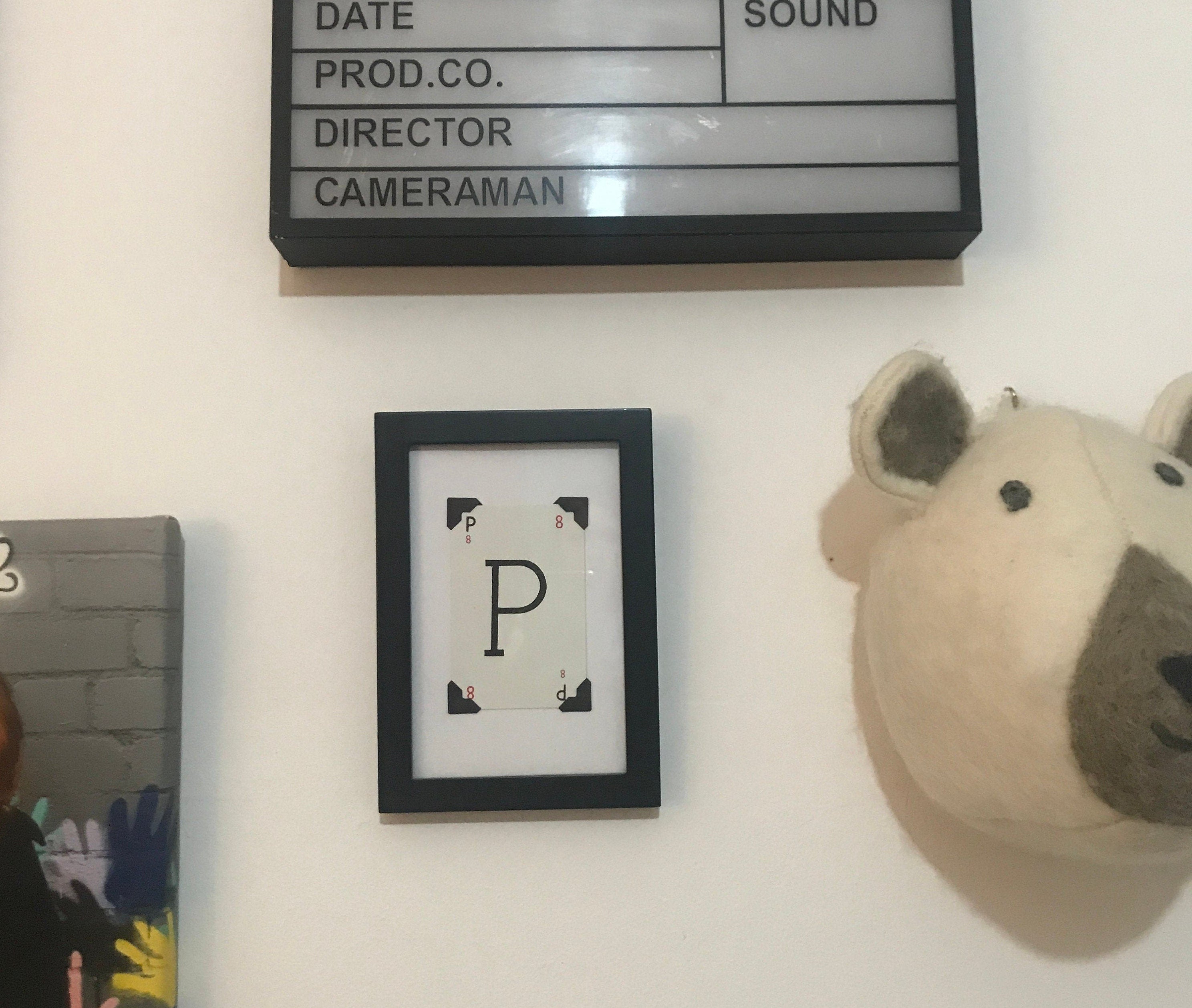 A black framed picture with a white letter P in the center. The letter P is surrounded by four black corners.