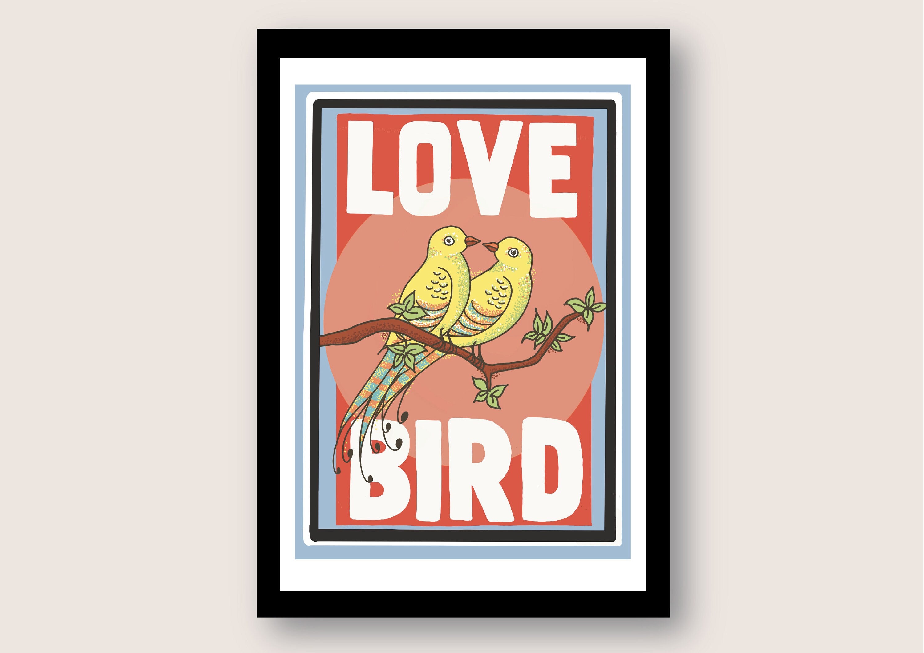 A black framed print against a white background. The print has a white border and features two yellow birds with their beaks touching sitting on a branch. the background behind the birds is pink. Large white text reads Love Bird all written in upper case letters.