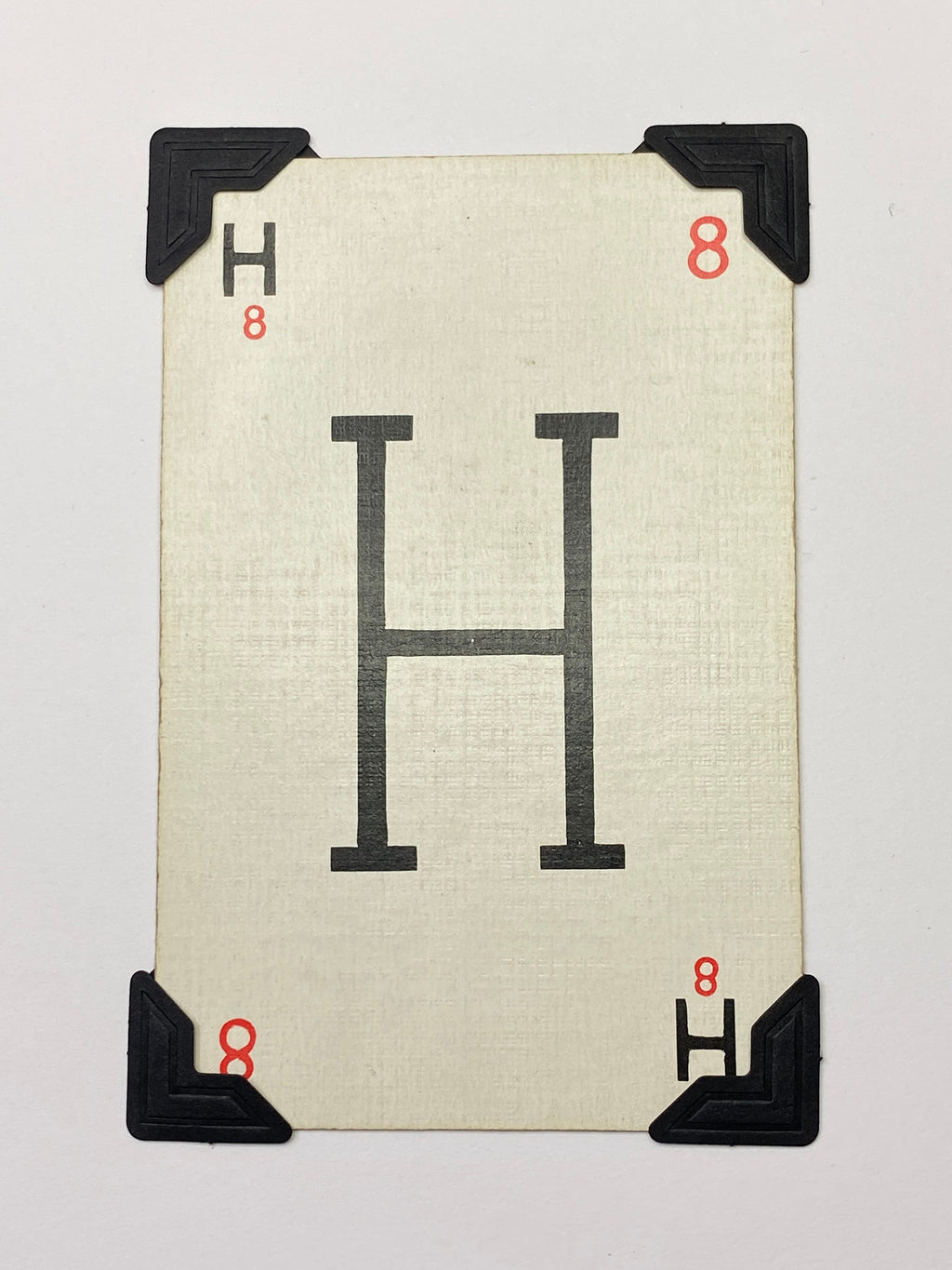 A white card with a black letter H printed on it. The card has black corner protectors.