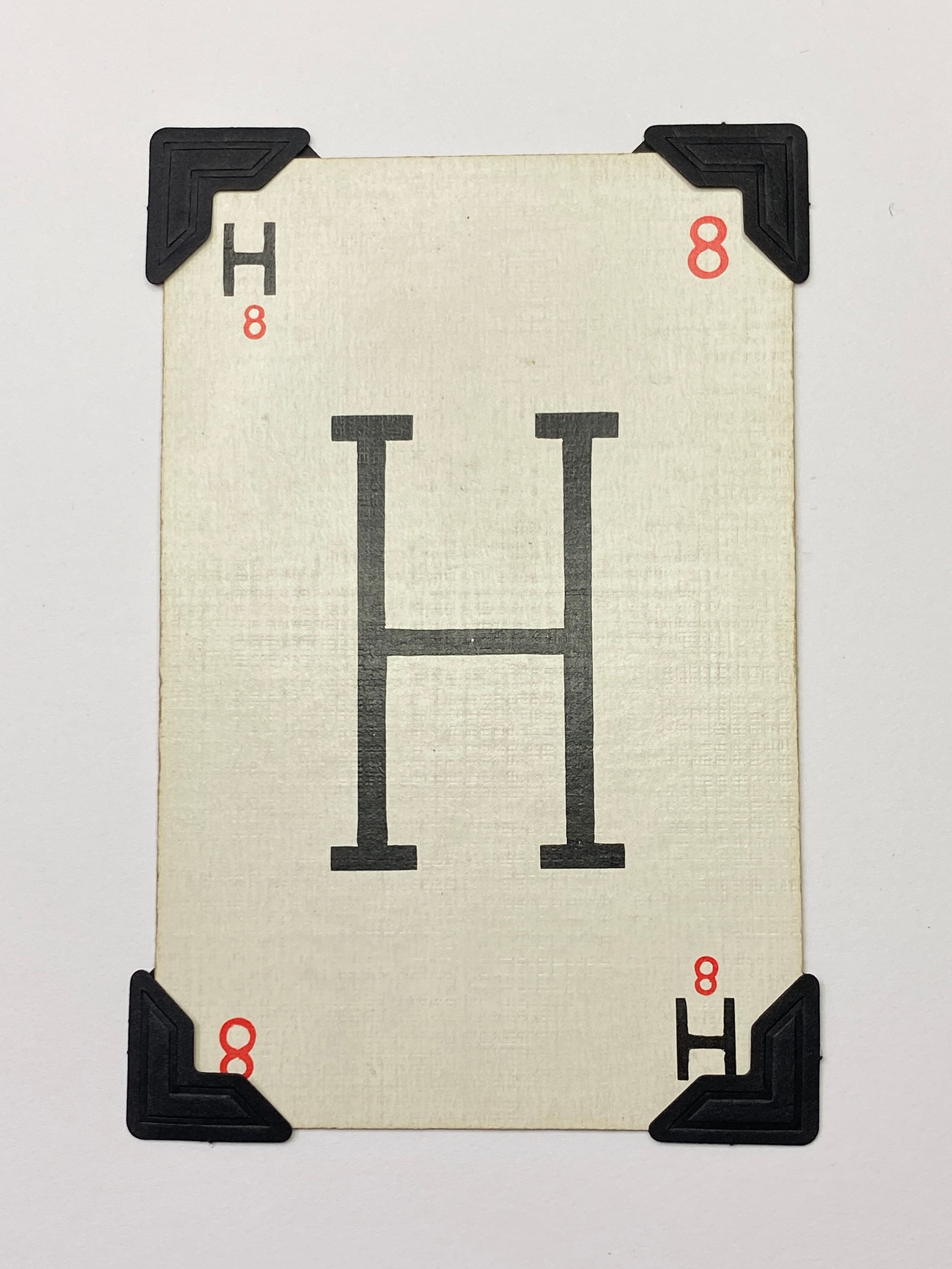A white card with a black letter H printed on it. The card has black corner protectors.