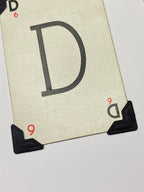 May include: A white card with the letter 'D' printed in black. The card has black corner protectors