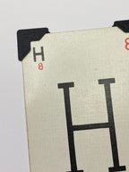 May include: A white card with a black letter H printed on it. The card has a black corner protector