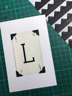 A white card with the letter L printed in black on it. The card has black corner protectors.