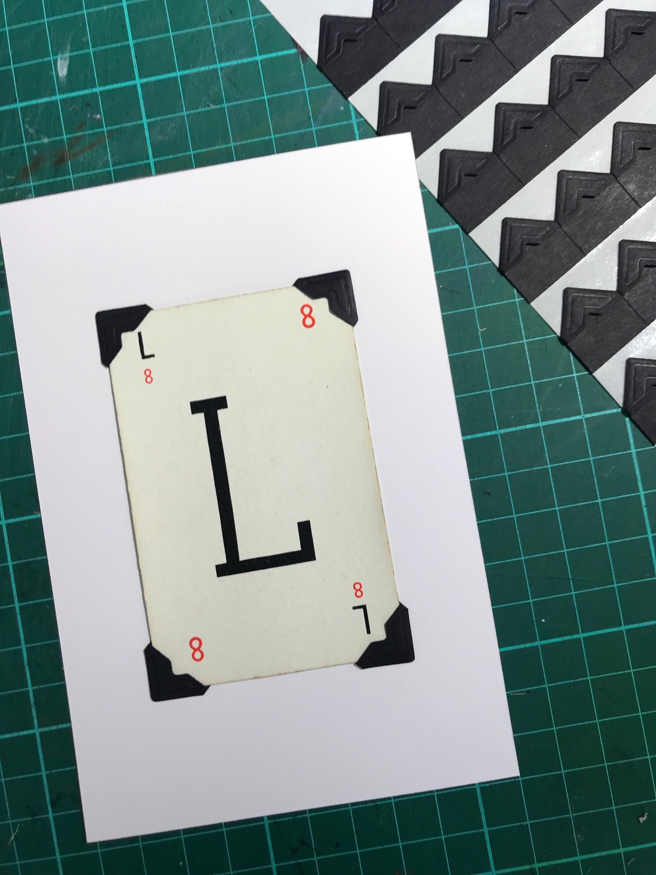 A white card with the letter L printed in black on it. The card has black corner protectors.